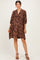 woman wearing a brown paisley print maternity dress with a loose fit and three-quarter sleeves, showing her baby bump