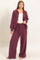 woman wearing a burgundy ribbed loungewear set consisting of a zip-up hoodie and wide-leg pants