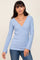 woman wearing a light blue long sleeve wrap top with a v-neck and bell sleeves paired with jeans