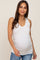 woman wearing a white maternity tank top and showing her baby bump while smiling