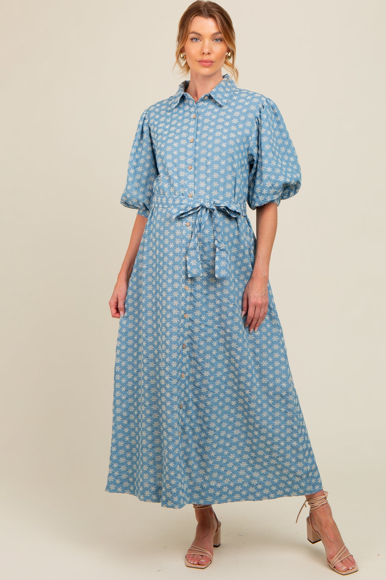 woman wearing a light blue floral button-up maternity dress with a tie belt and puff sleeves
