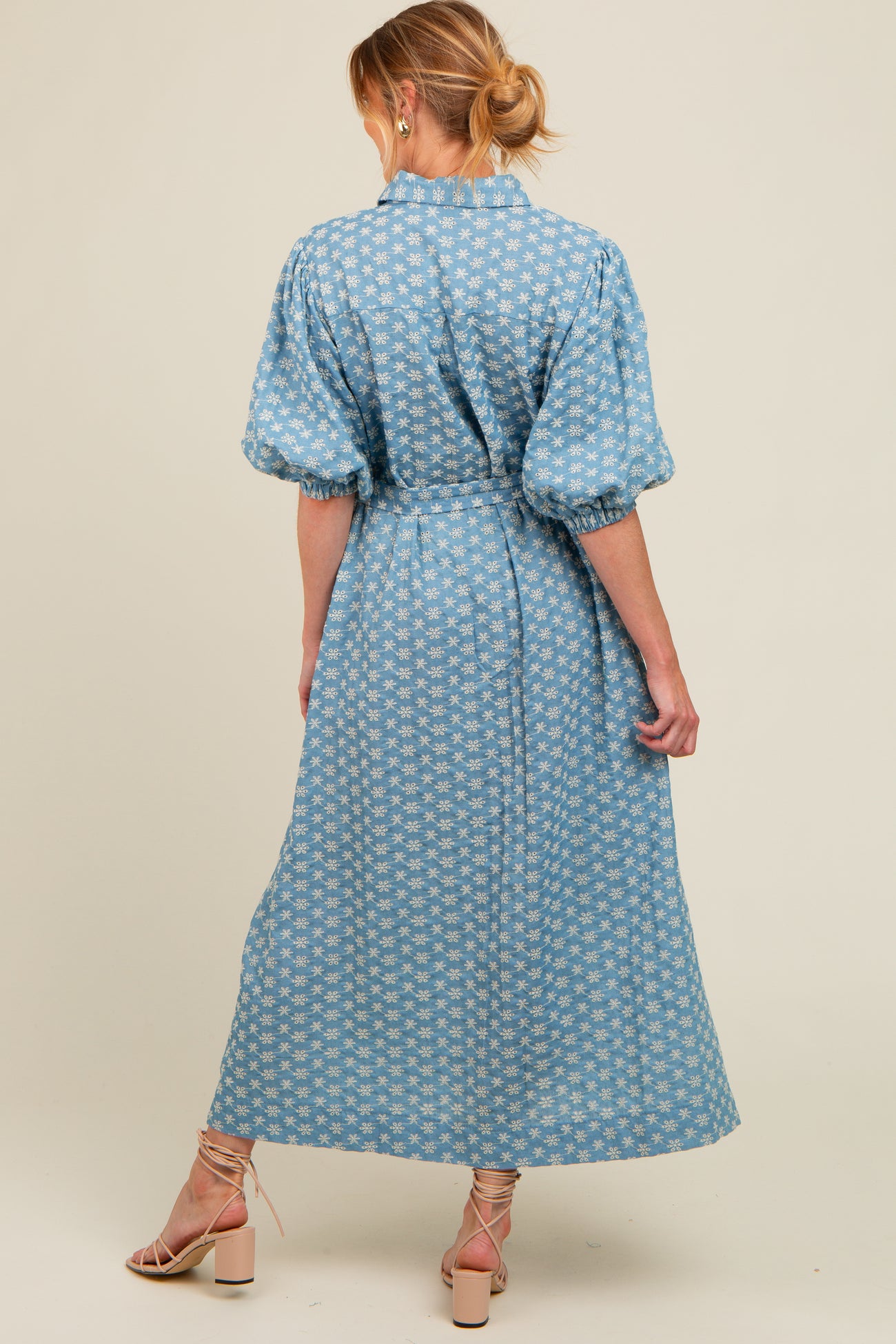 woman wearing a blue floral print maternity dress with puff sleeves and a cinched waist, showing baby bump from the back