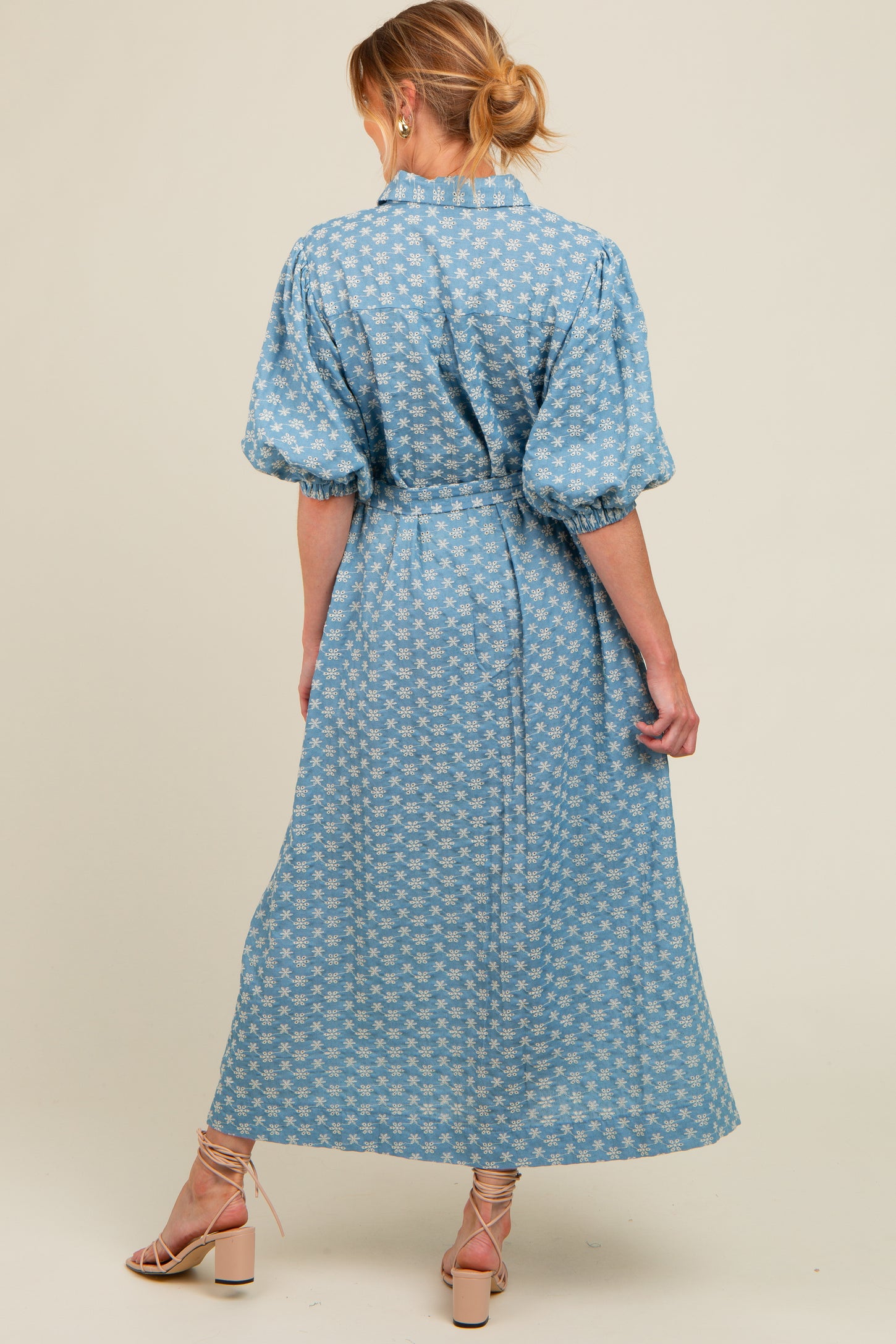 woman wearing a blue floral print maternity dress with puff sleeves and a cinched waist, showing baby bump from the back