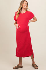woman wearing a red ribbed maternity dress with short sleeves and side slits, holding her baby bump