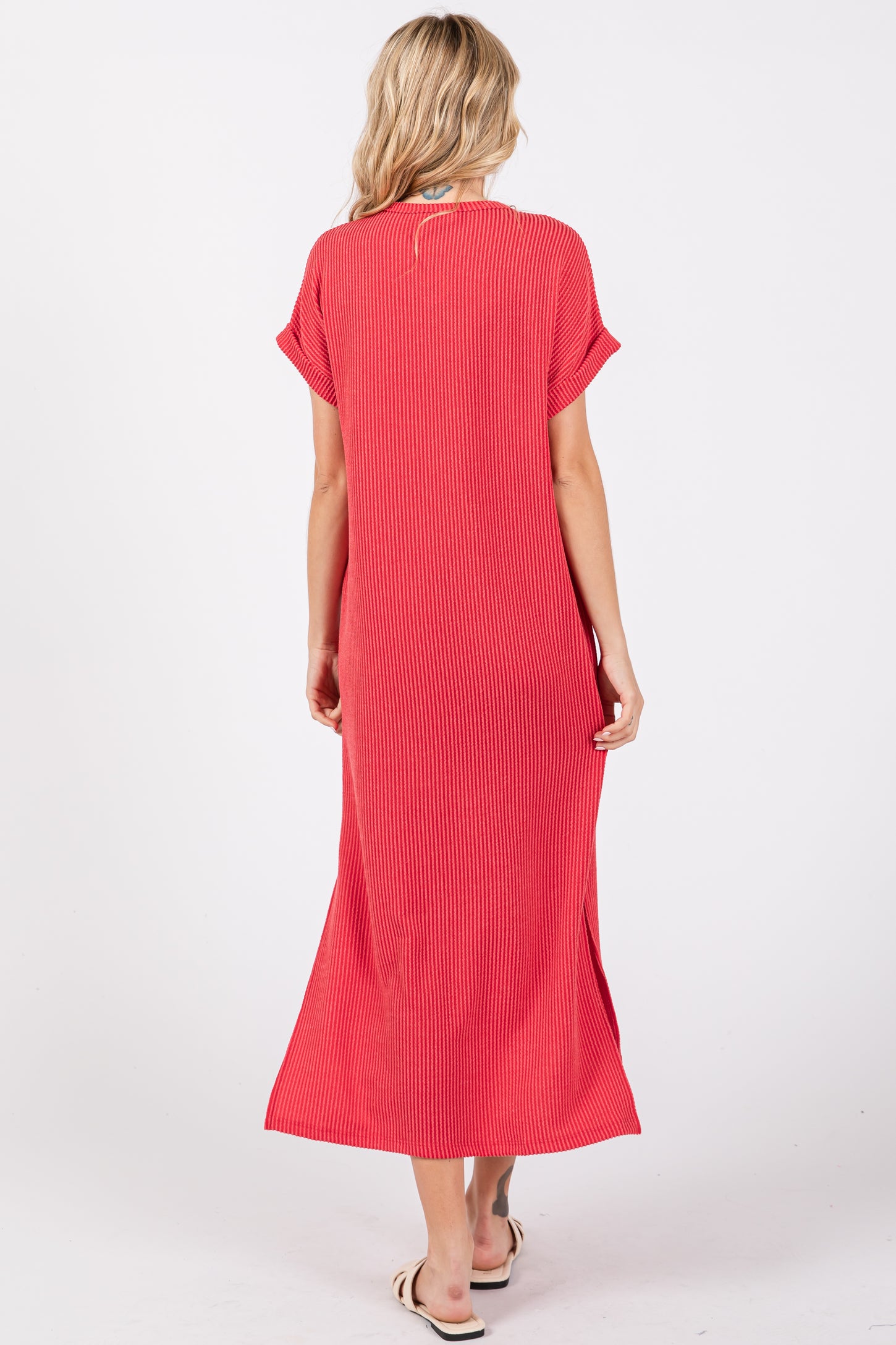 woman wearing a red striped maxi dress with short sleeves and side slits, viewed from the back
