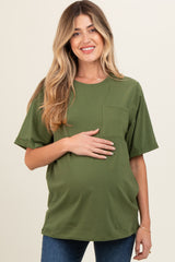 woman wearing a green short sleeve maternity top with a pocket and holding her baby bump