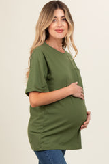woman wearing a green short sleeve maternity top and holding her baby bump