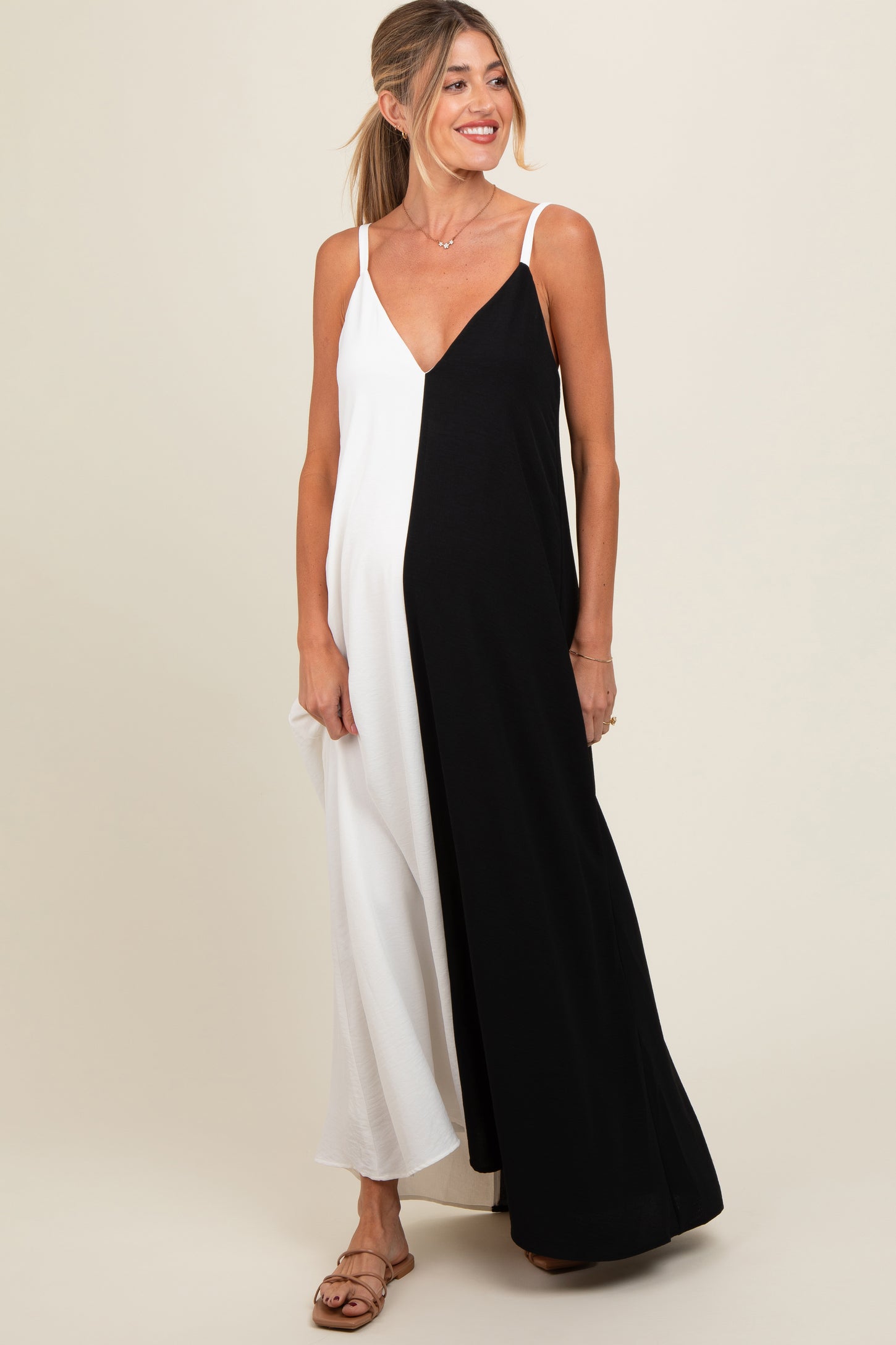 woman wearing a black and white color block maternity dress with spaghetti straps and a flowy silhouette