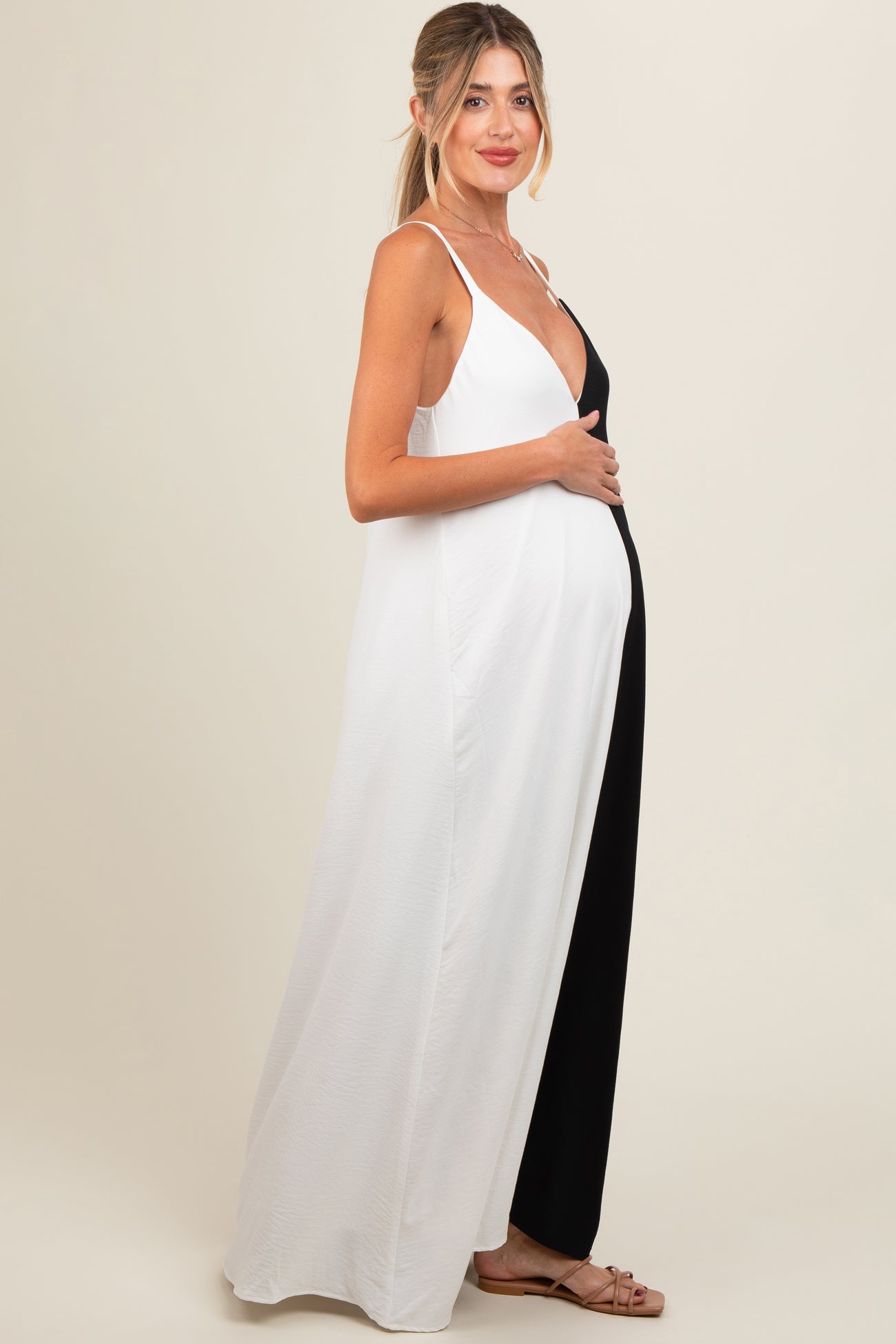 woman wearing a black and white color block maternity maxi dress and holding her baby bump