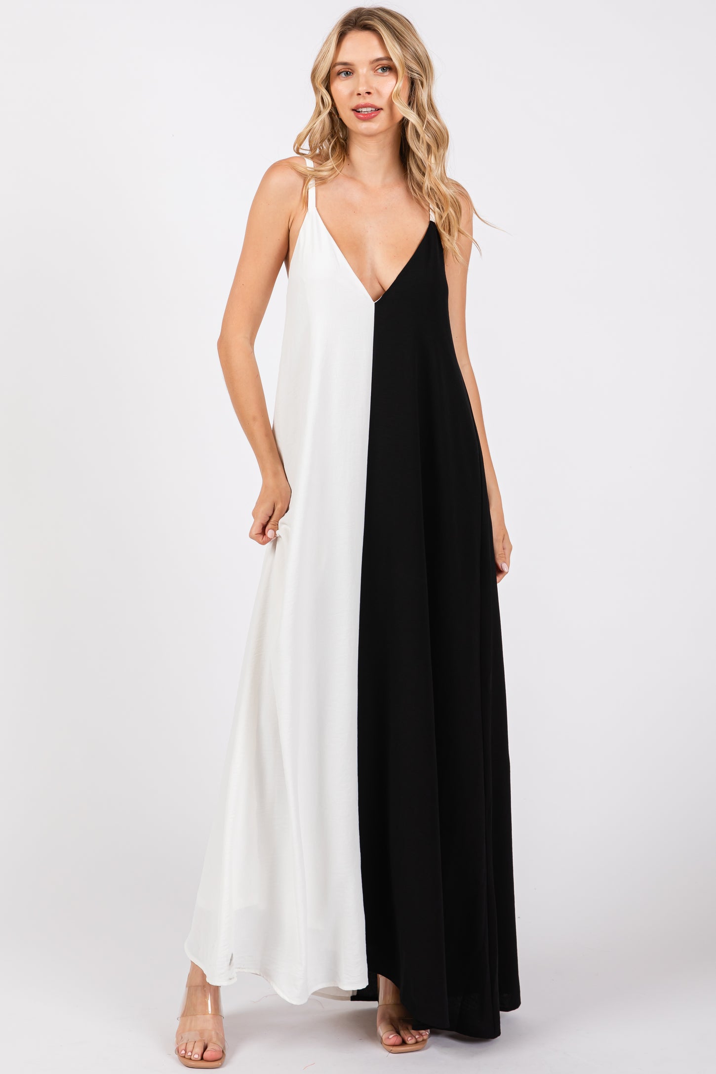 woman wearing a black and white color block maxi dress with a deep v-neck and thin straps