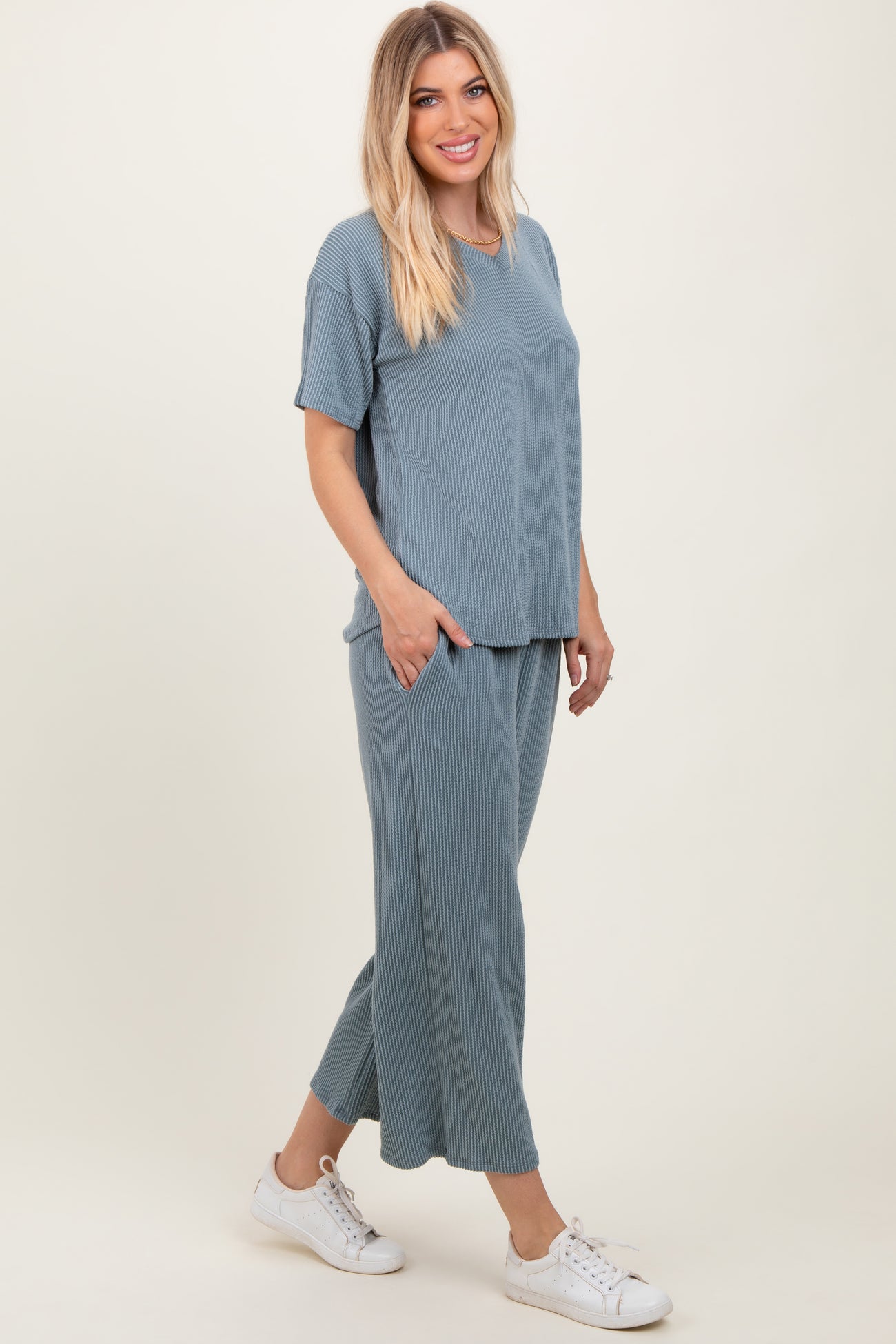 woman wearing a sky blue ribbed two-piece lounge set with a short sleeve top and wide-leg pants, styled with white sneakers