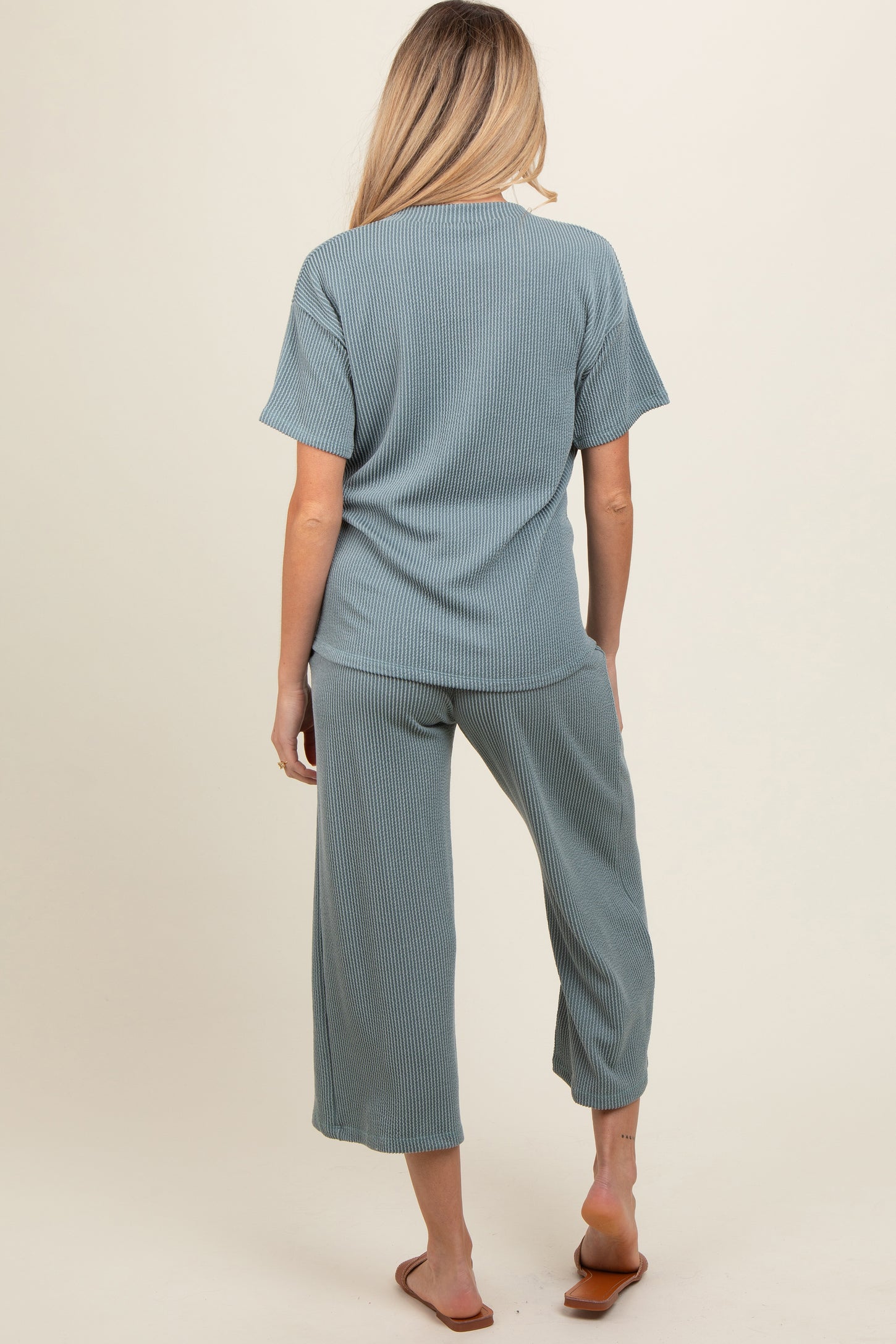 woman wearing a green ribbed maternity top and matching cropped pants, showing a relaxed fit from the back