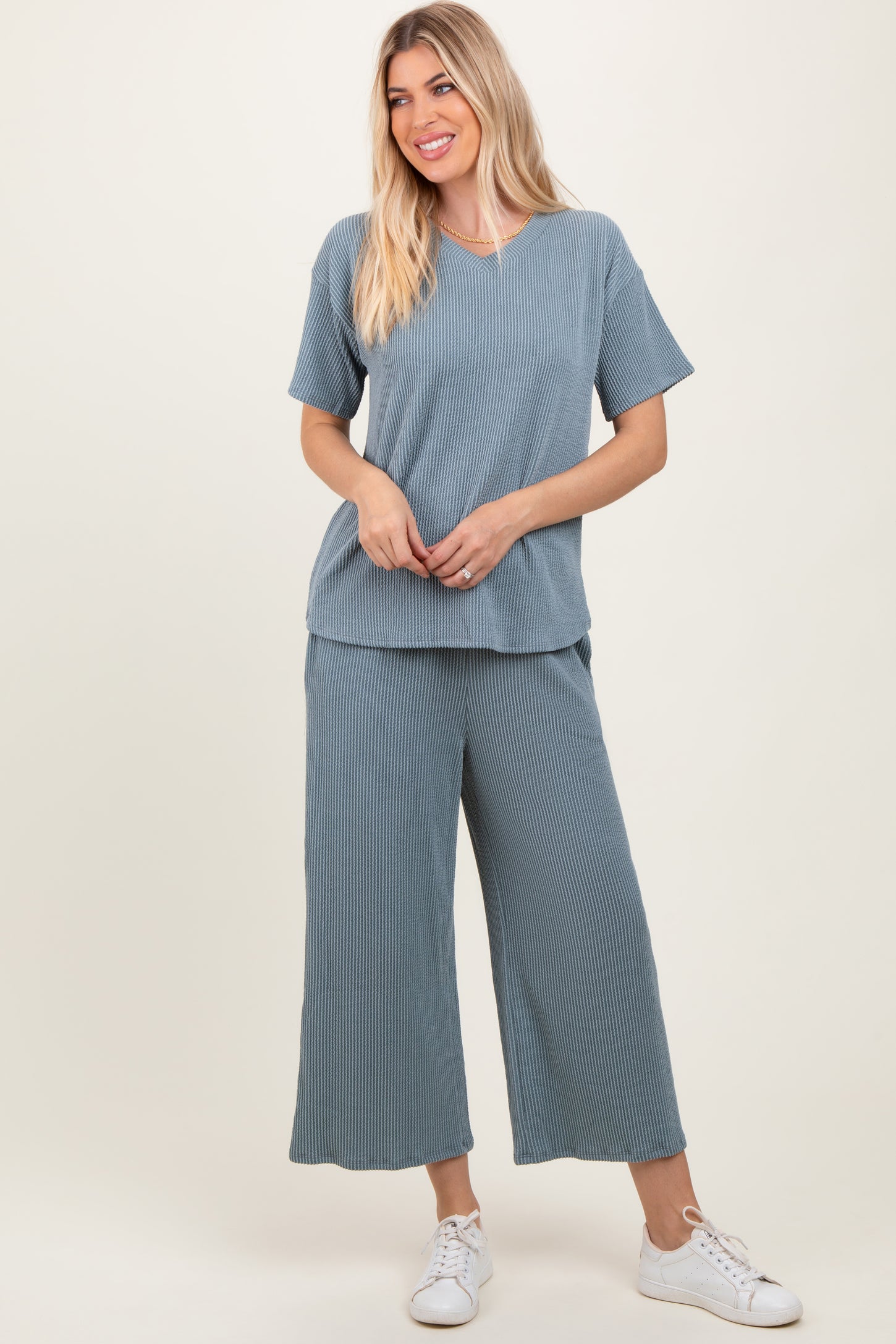 woman wearing a light blue textured v-neck top and matching wide-leg pants with white sneakers
