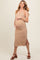 woman wearing a beige ribbed maternity dress with side slits and holding her baby bump