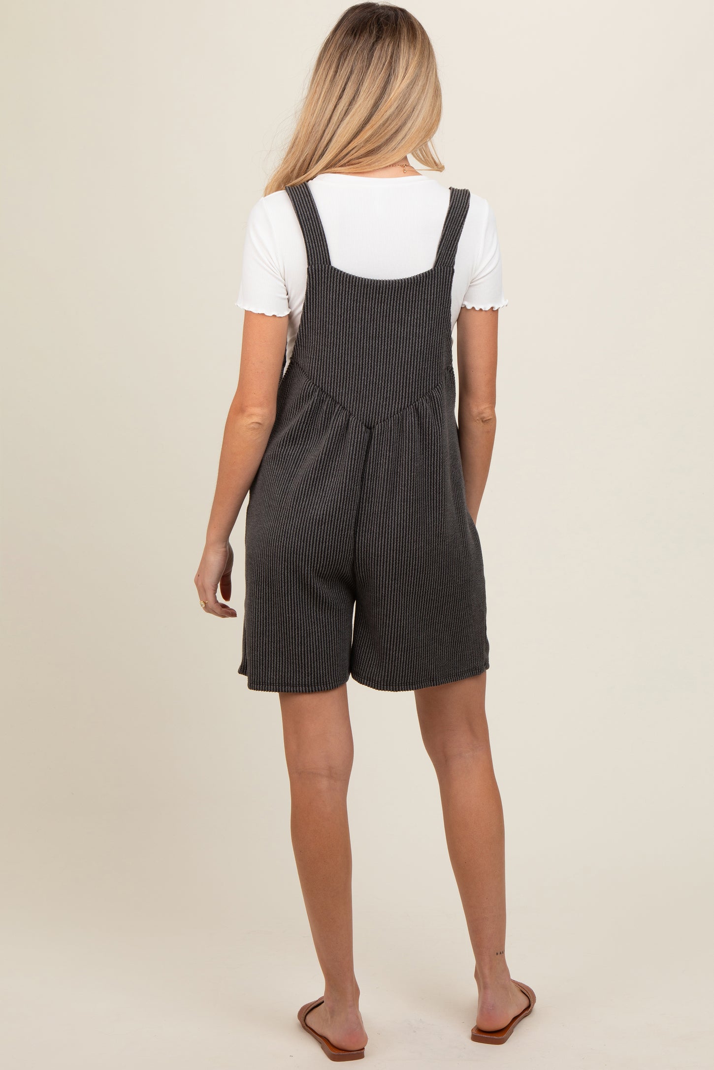 woman wearing a black and white striped maternity romper with a relaxed fit and adjustable straps, showing her back