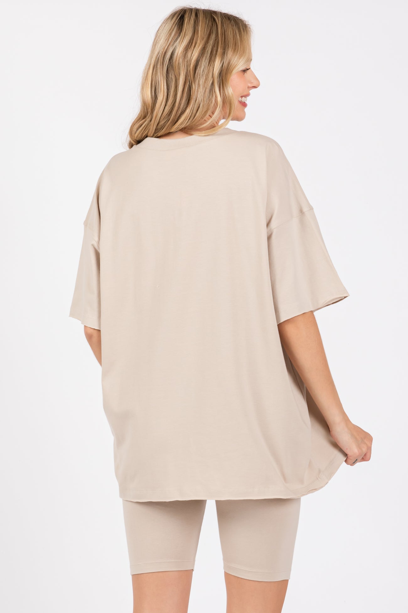 woman wearing a beige oversized t-shirt with back view, styled with matching beige biker shorts