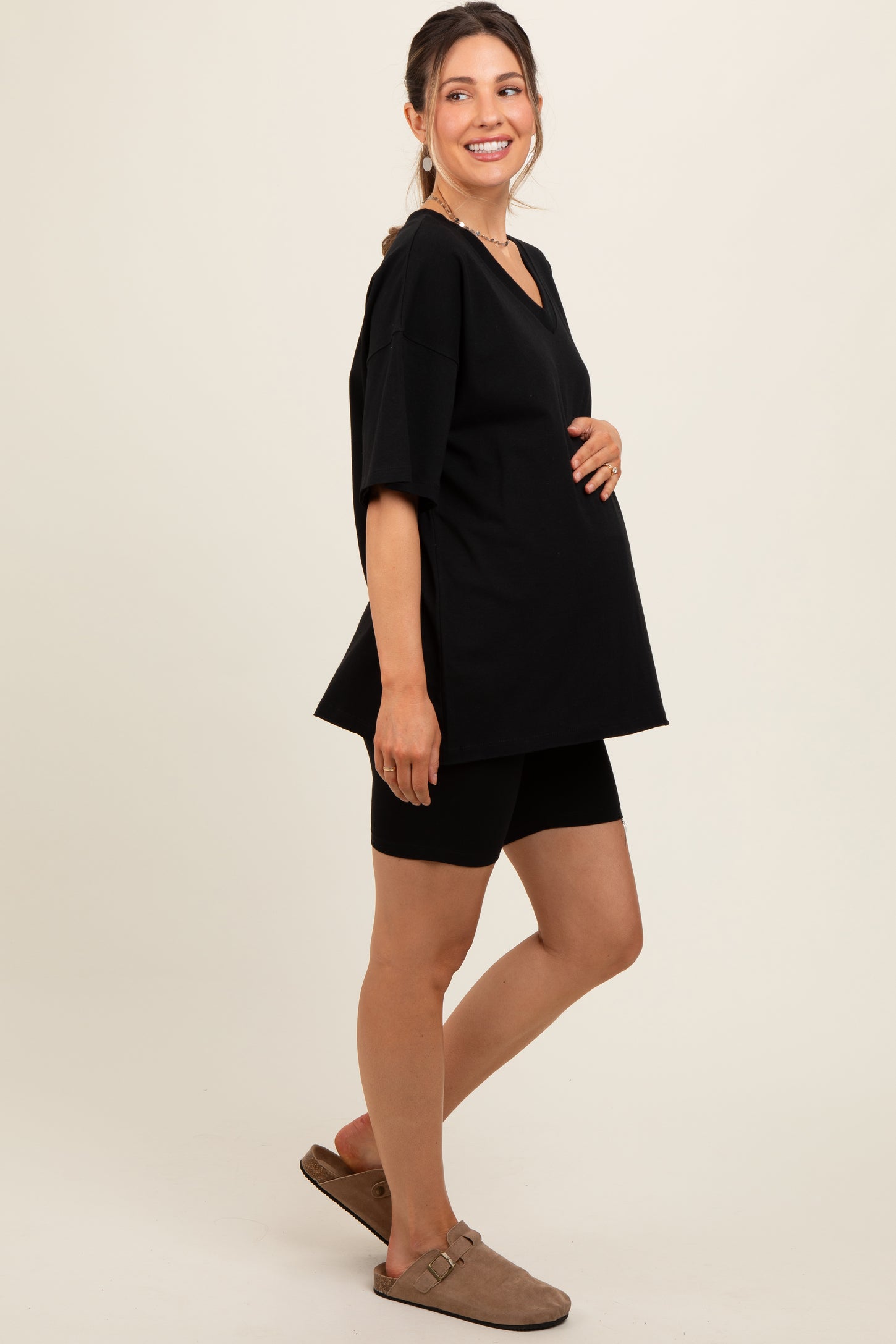 woman wearing a black oversized maternity top and black shorts, showcasing her baby bump