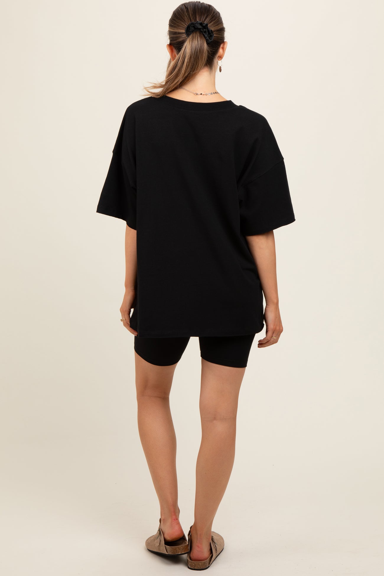 woman wearing a black oversized maternity t-shirt and black bike shorts, viewed from the back