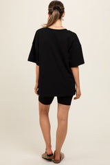 woman wearing a black oversized maternity t-shirt and black bike shorts, viewed from the back