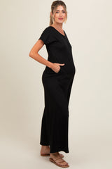 woman wearing a black ribbed maternity jumpsuit with pockets and a visible baby bump