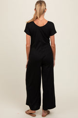 woman wearing a black maternity jumpsuit with a ribbed texture and wide legs, showing the back view