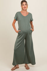 woman wearing a green ribbed maternity jumpsuit with short sleeves and pockets, highlighting her baby bump