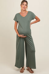 woman wearing a green ribbed maternity jumpsuit and holding her baby bump