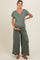 woman wearing a green ribbed maternity jumpsuit and holding her baby bump