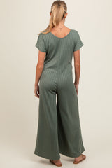 woman wearing a muted green maternity jumpsuit with short sleeves and wide leg, seen from the back