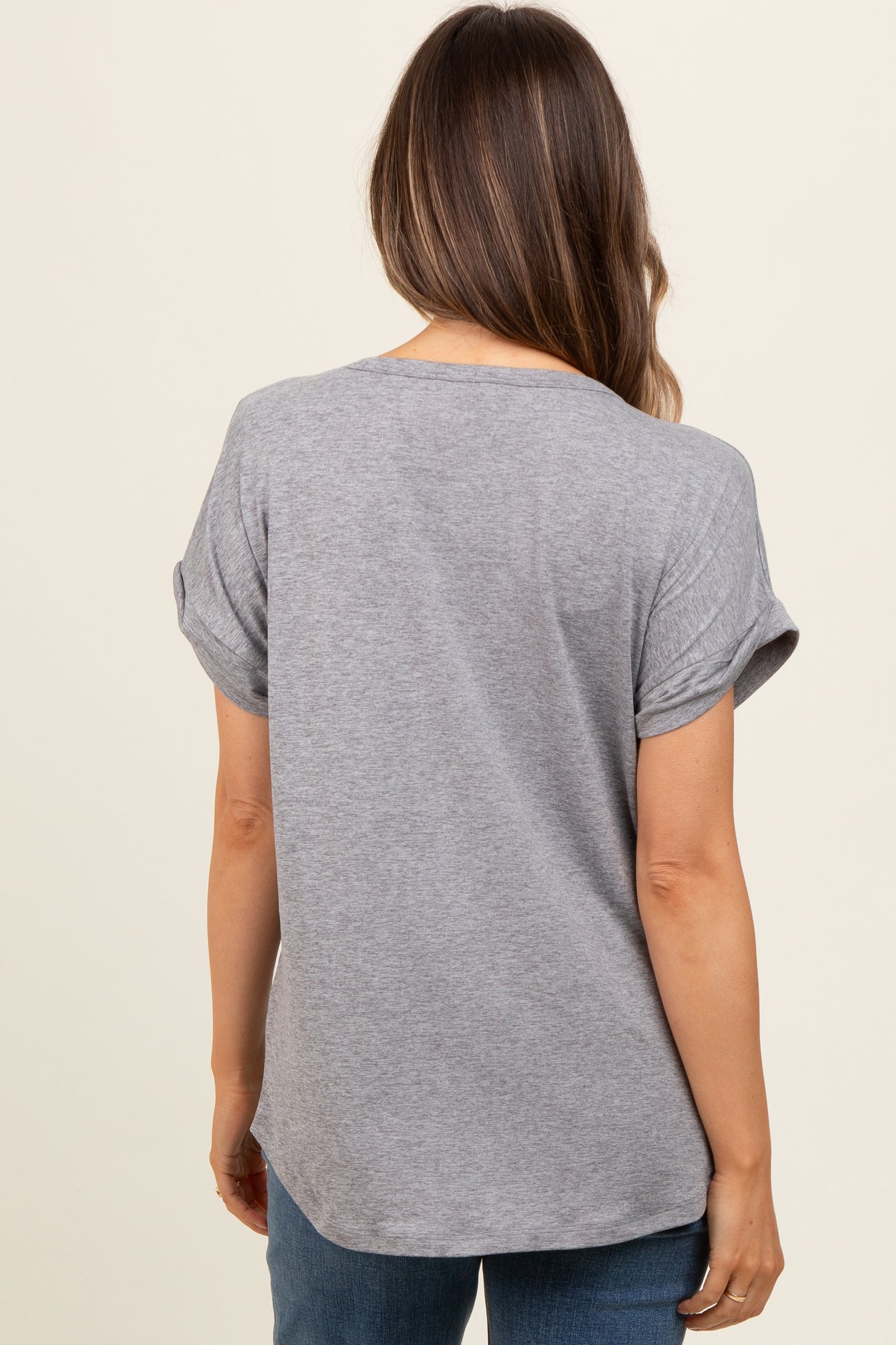woman wearing a gray short sleeve maternity top with rolled sleeves, showing the back view