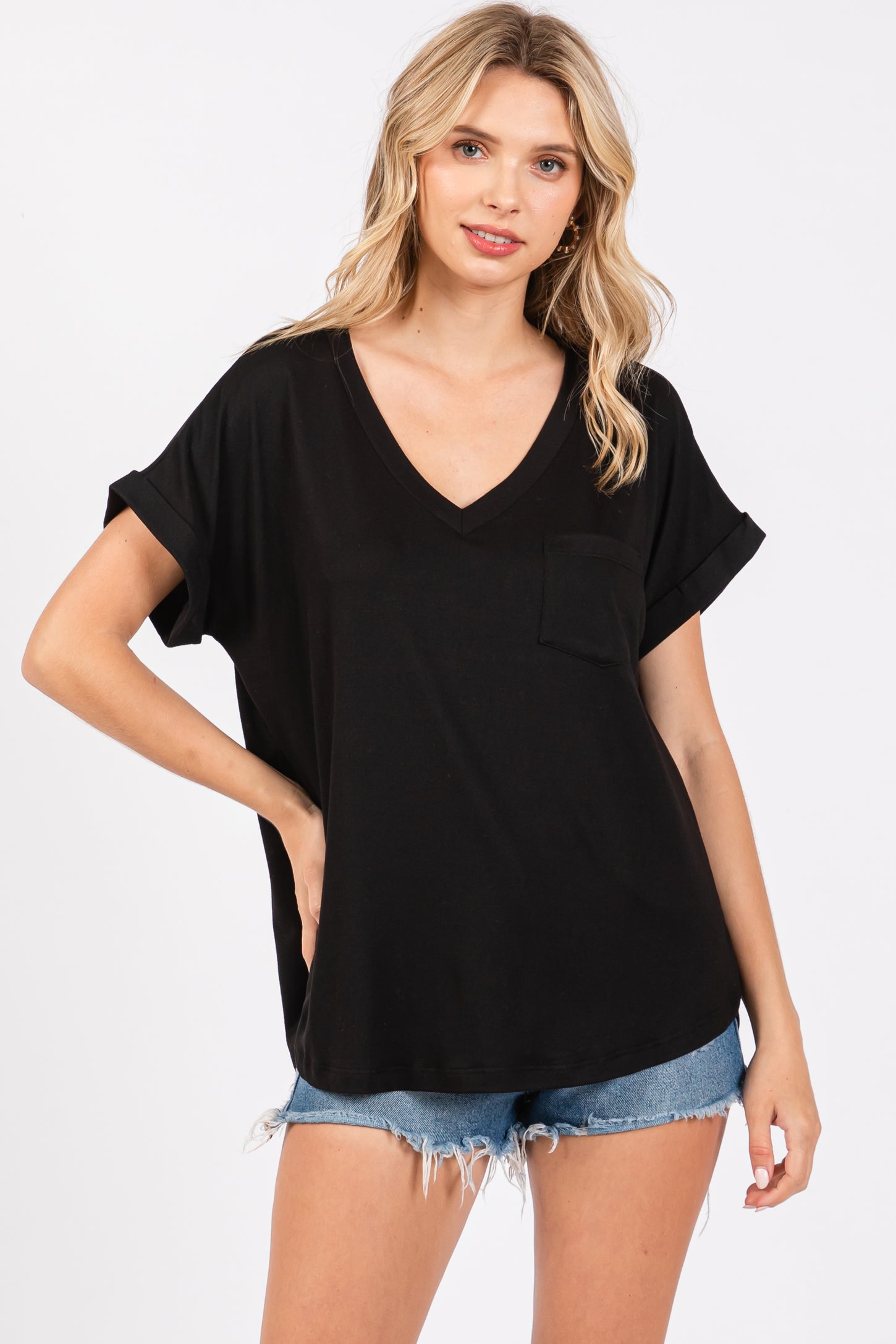 woman wearing a black v-neck t-shirt with rolled sleeves and a front pocket, paired with denim shorts