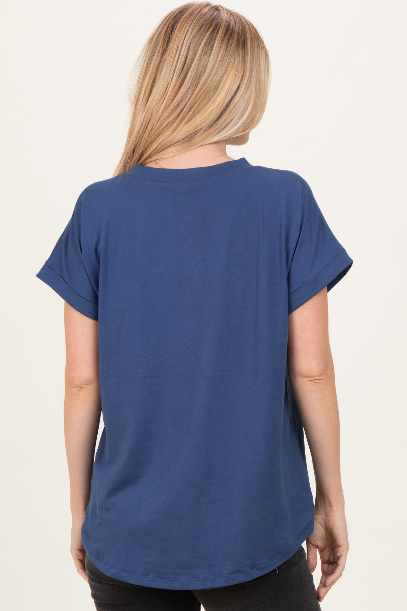 woman wearing a blue short sleeve top with rolled cuffs, shown from the back