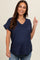 woman wearing a navy blue short sleeve maternity top with a v-neck and pocket, showing her baby bump