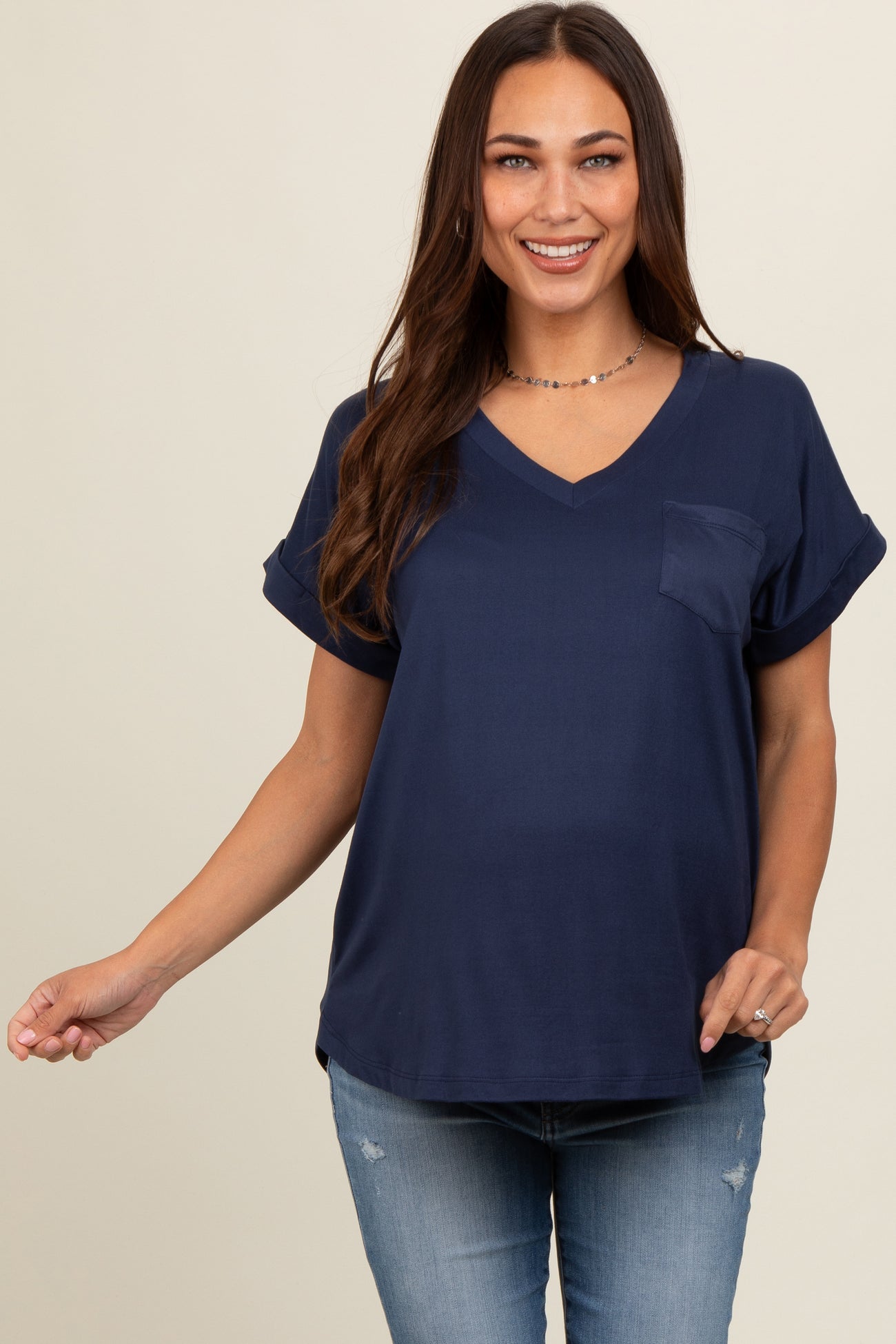 woman wearing a navy blue maternity top with short sleeves and a pocket, smiling at the camera