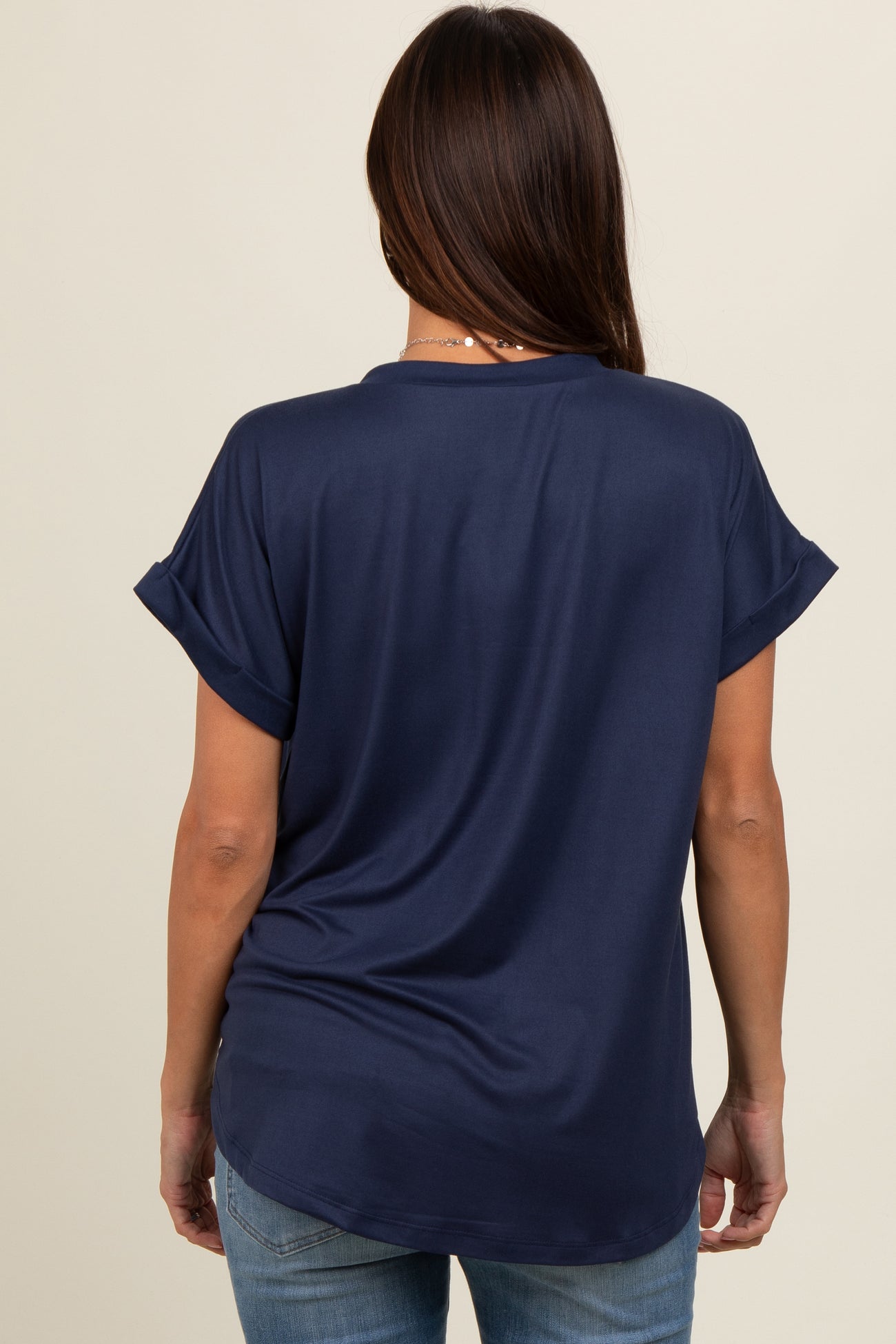 woman wearing a navy blue maternity top with rolled short sleeves, seen from the back
