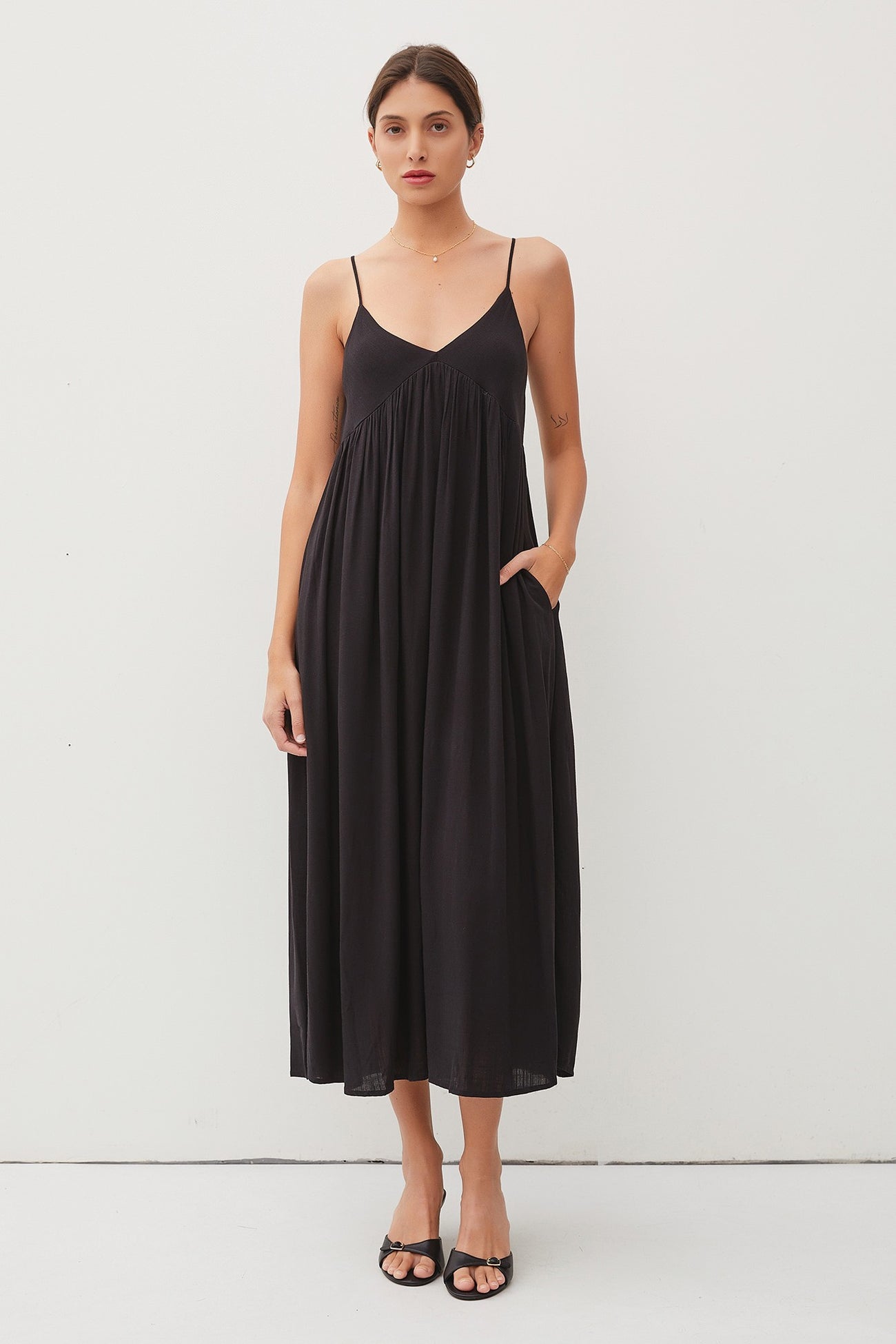 woman wearing a black sleeveless maxi dress with pockets and a flowy silhouette