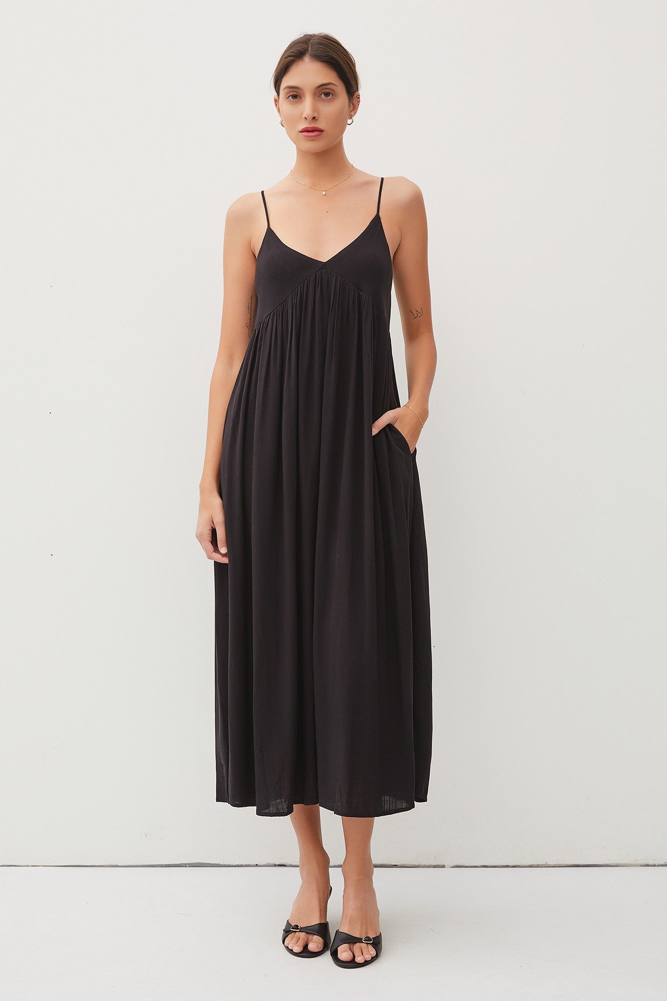 woman wearing a black sleeveless maxi dress with pockets and a flowy silhouette