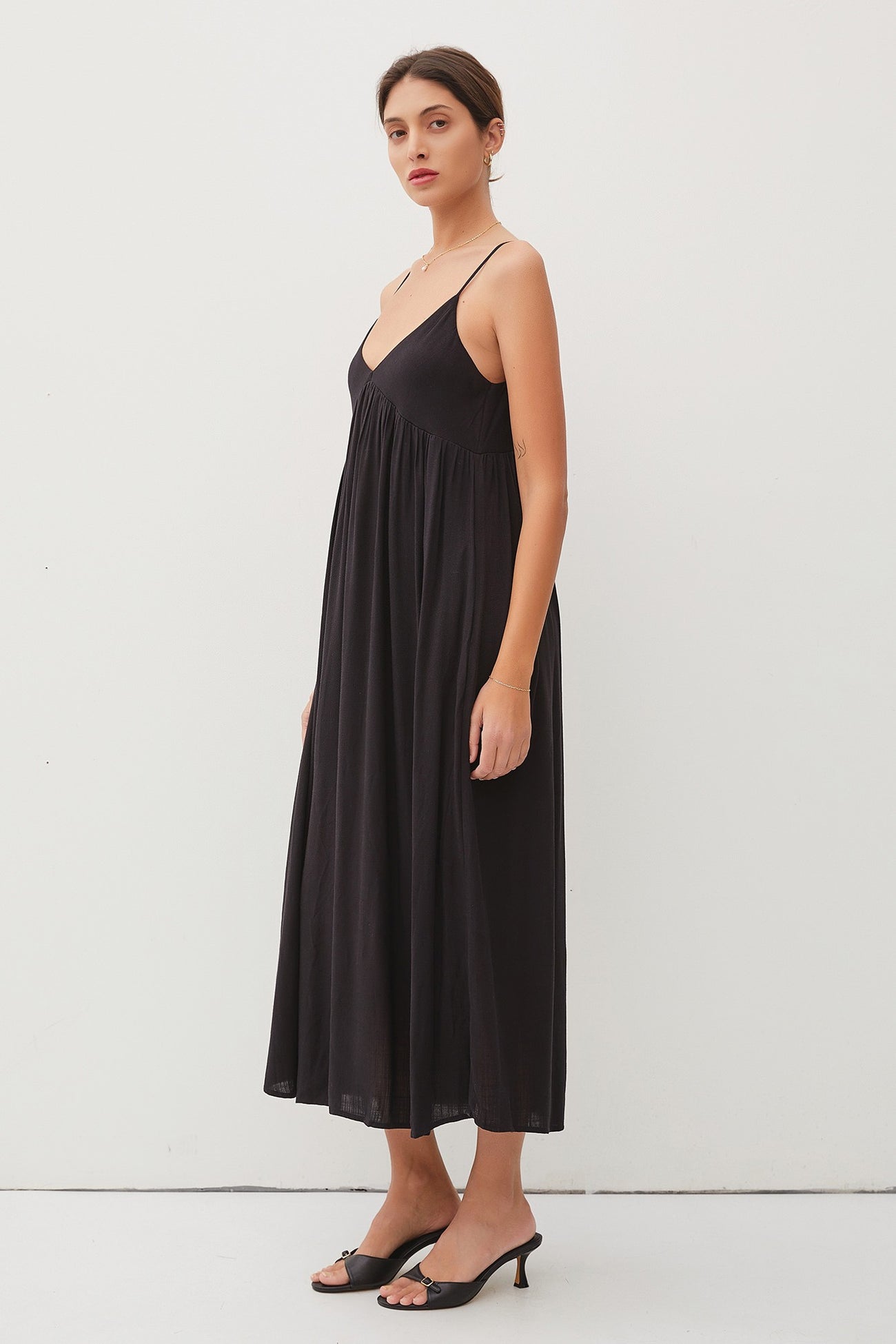 woman wearing a black spaghetti strap maxi dress with a flowy silhouette and a relaxed fit