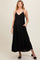 woman wearing a black maternity maxi dress with adjustable straps and pockets, showcasing her baby bump