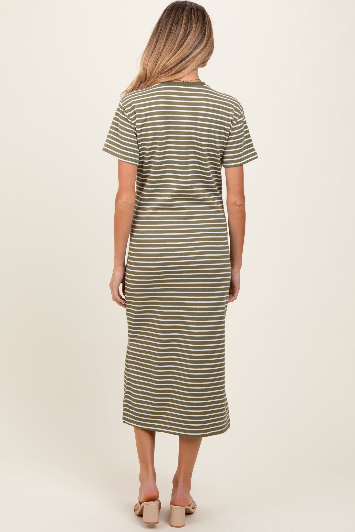 woman wearing a green and white striped maternity dress with short sleeves and a midi length, seen from the back