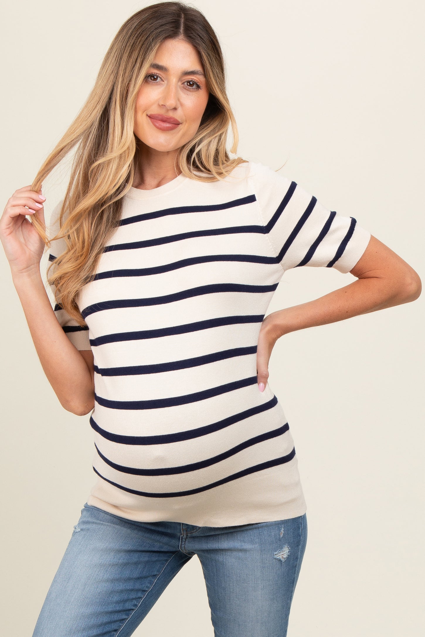 woman wearing a cream and navy striped maternity top with short sleeves and a visible baby bump