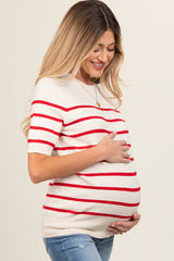 woman wearing a cream and red striped maternity top and holding her baby bump