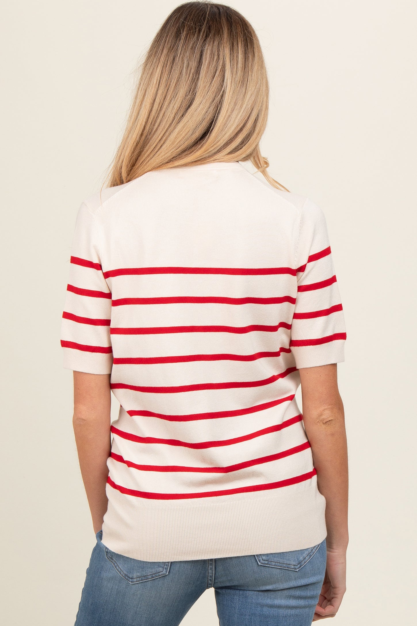 woman wearing a cream and red striped maternity sweater with short sleeves, viewed from the back