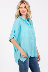 woman wearing a light blue oversized button-up shirt paired with dark jeans