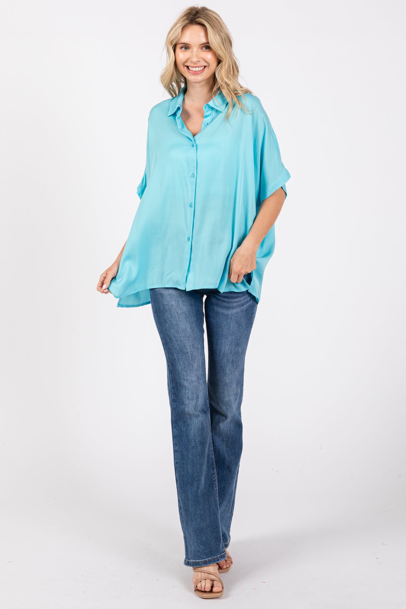 woman wearing a relaxed fit turquoise button-up shirt paired with flared jeans and sandals