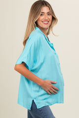 woman wearing a light blue short sleeve maternity top and holding her baby bump