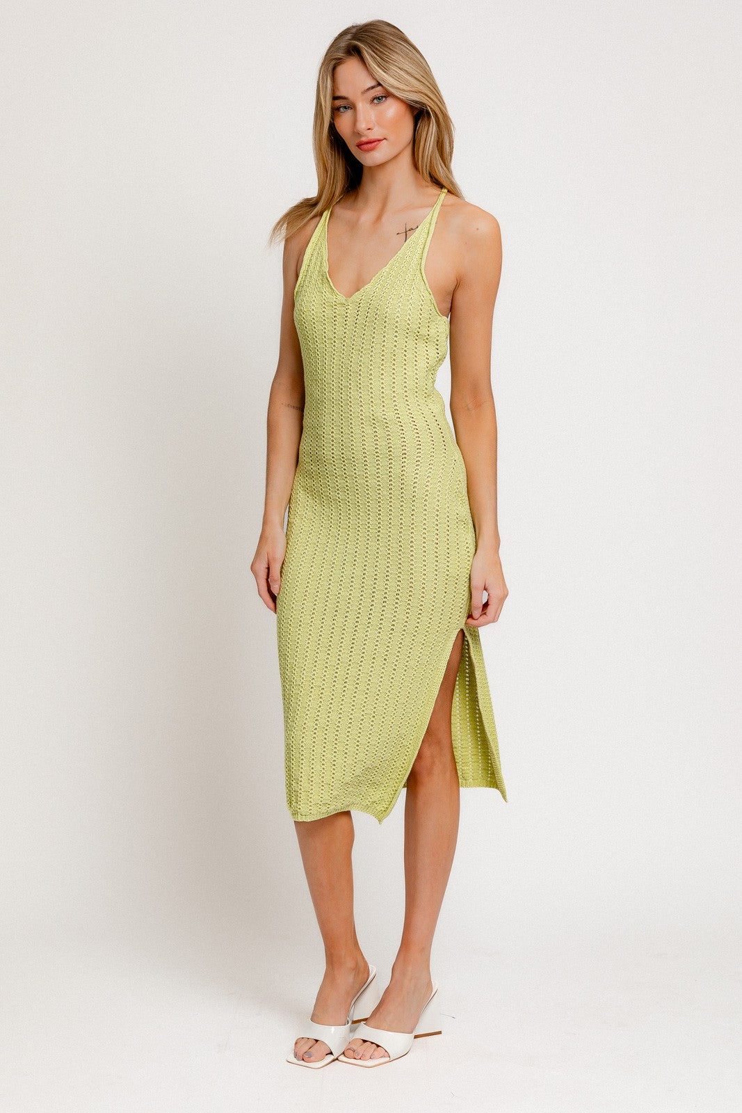 woman wearing a light green knitted midi dress with side slit and thin straps