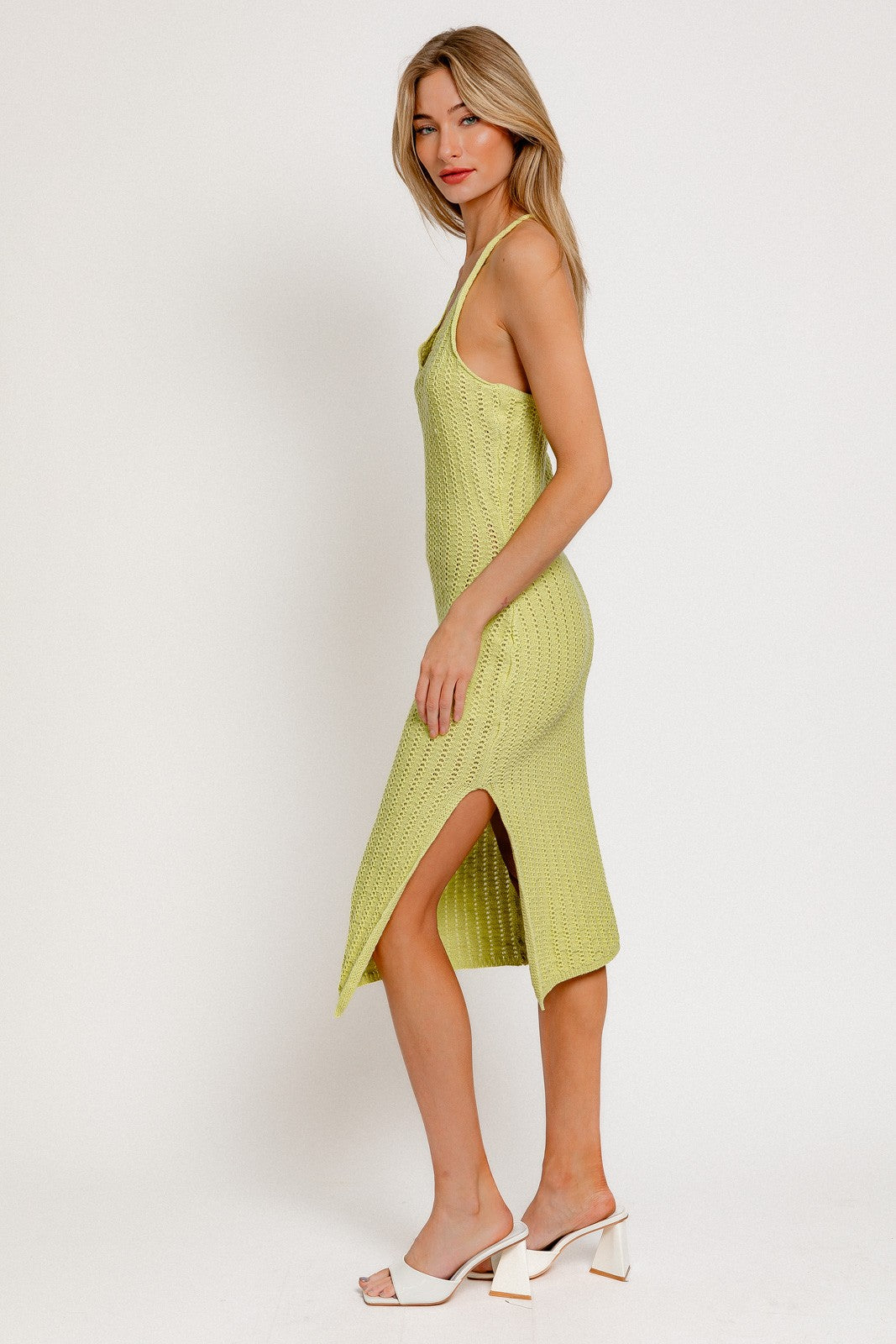 woman wearing a light green knitted midi dress with side slits and spaghetti straps