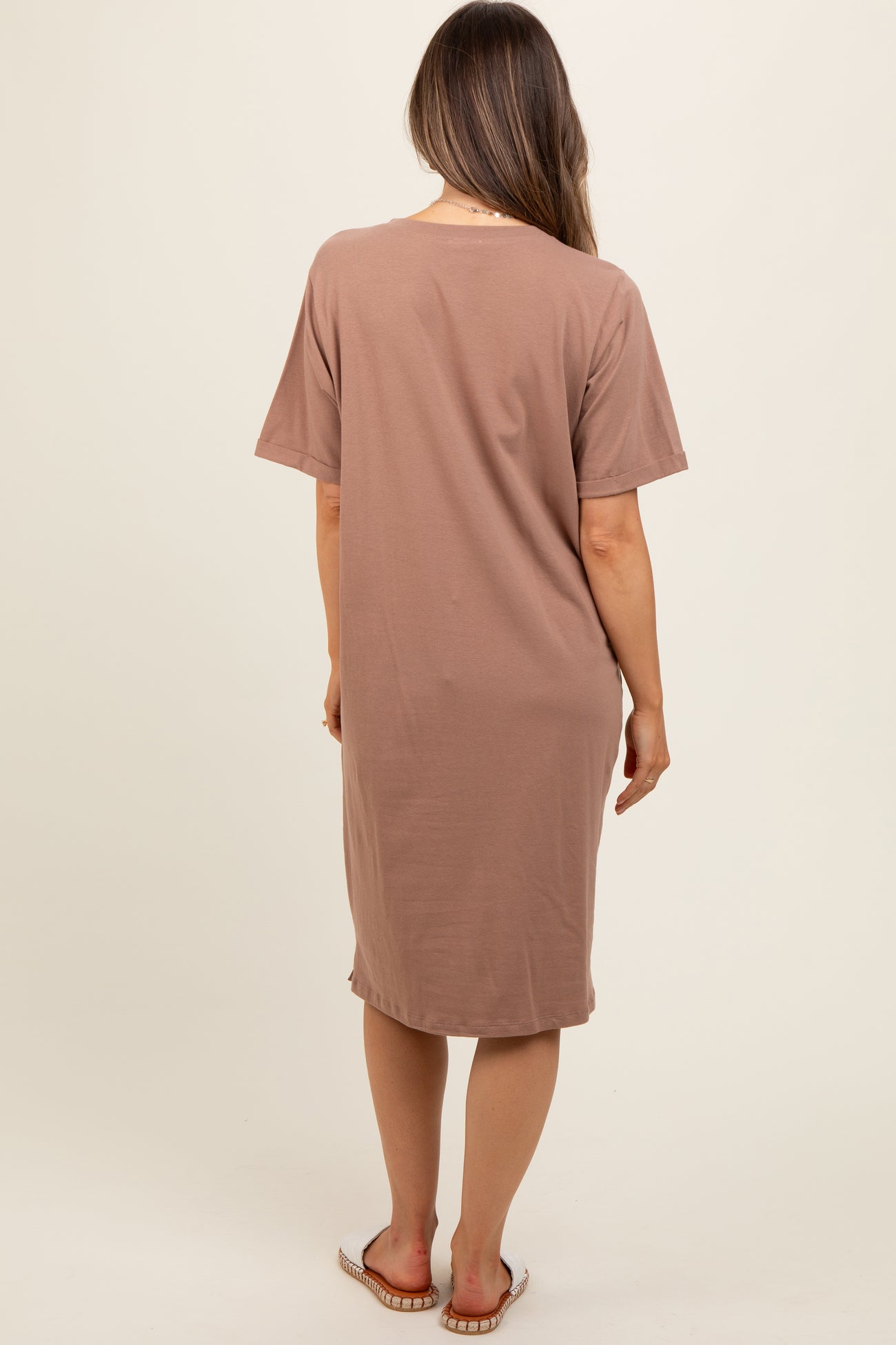woman wearing a light brown maternity dress with short sleeves, viewed from the back