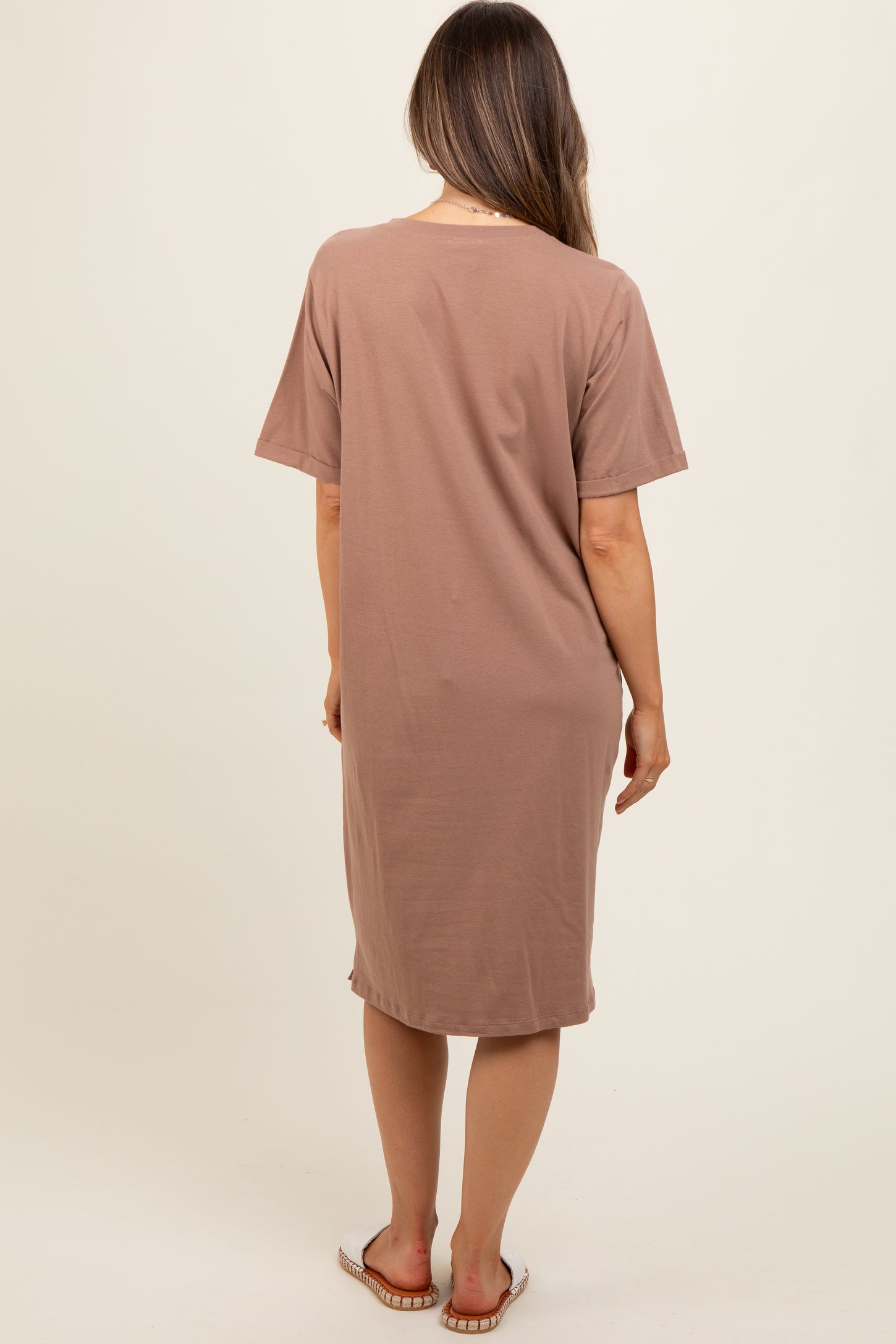 woman wearing a light brown maternity dress with short sleeves, viewed from the back
